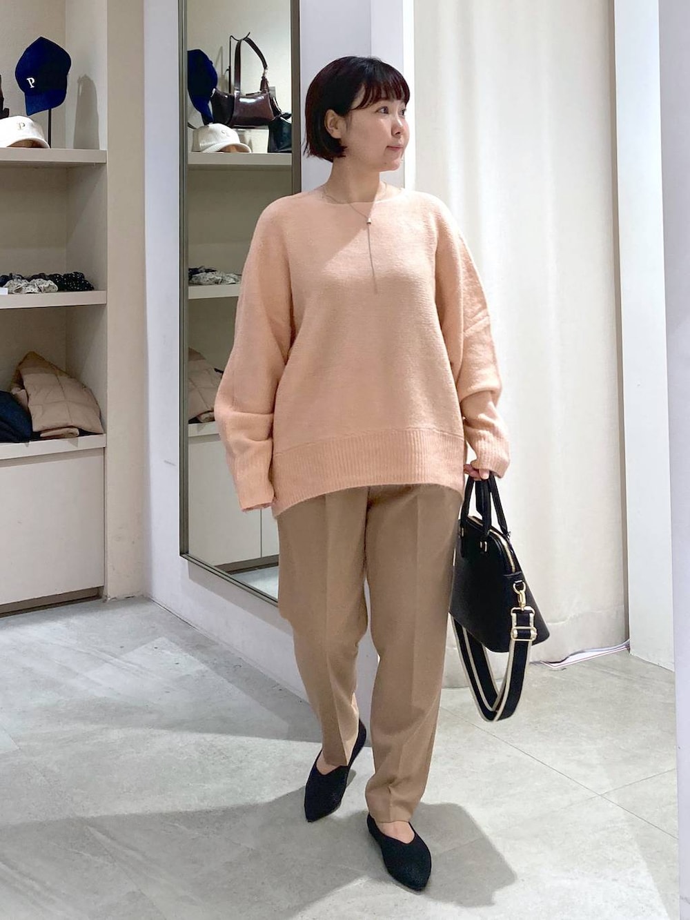 ブラック系のハンドバッグ、ピンク系のニット/セーター、ベージュ系のスラックスを着用したレディースの秋コーディネートの5枚目の写真