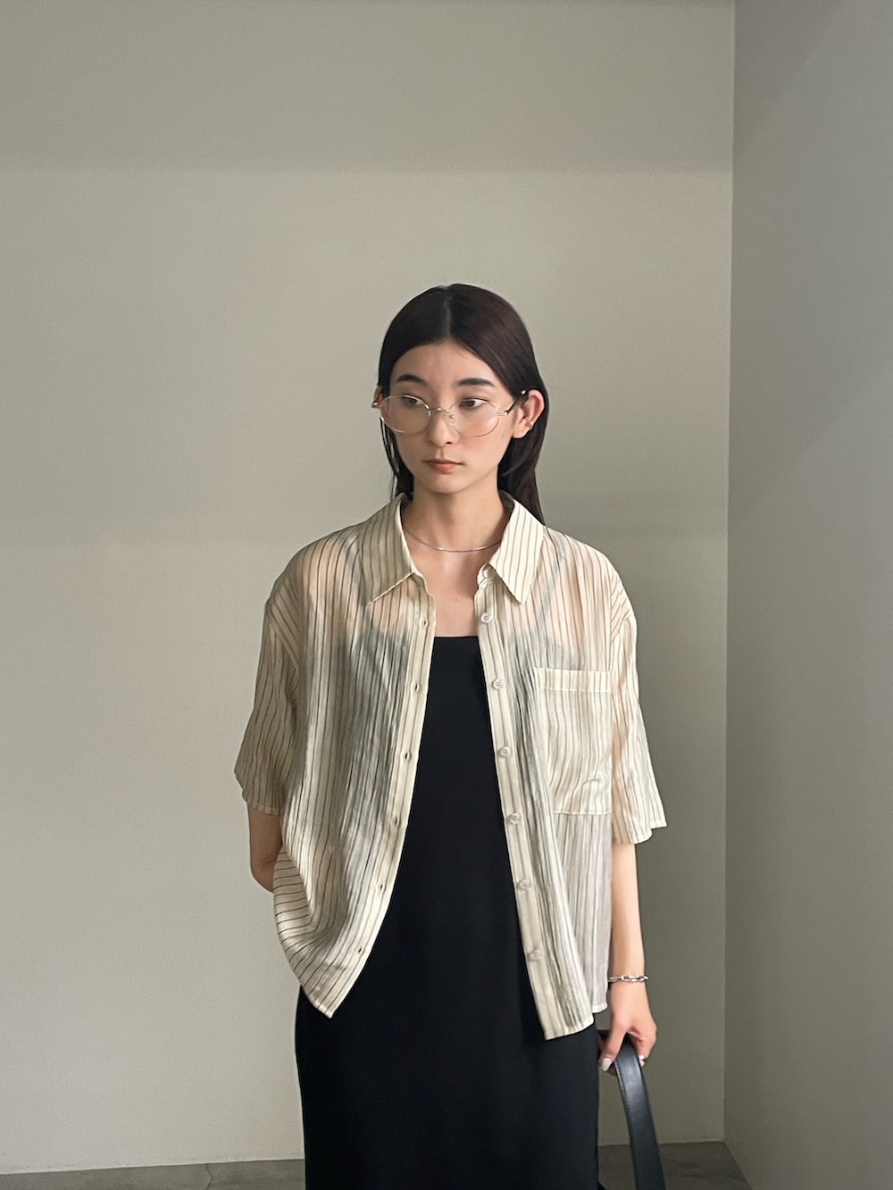 ブラック系のワンピース、ベージュ系のシャツ/ブラウス、シルバー系のブレスレットを着用したレディースの春コーディネートの6枚目の写真