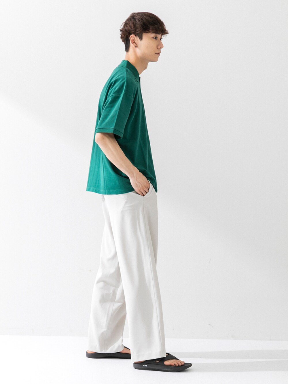 ブラック系のサンダル、ベージュ系のスラックス、グリーン系のポロシャツを着用したメンズの夏コーディネートの2枚目の写真