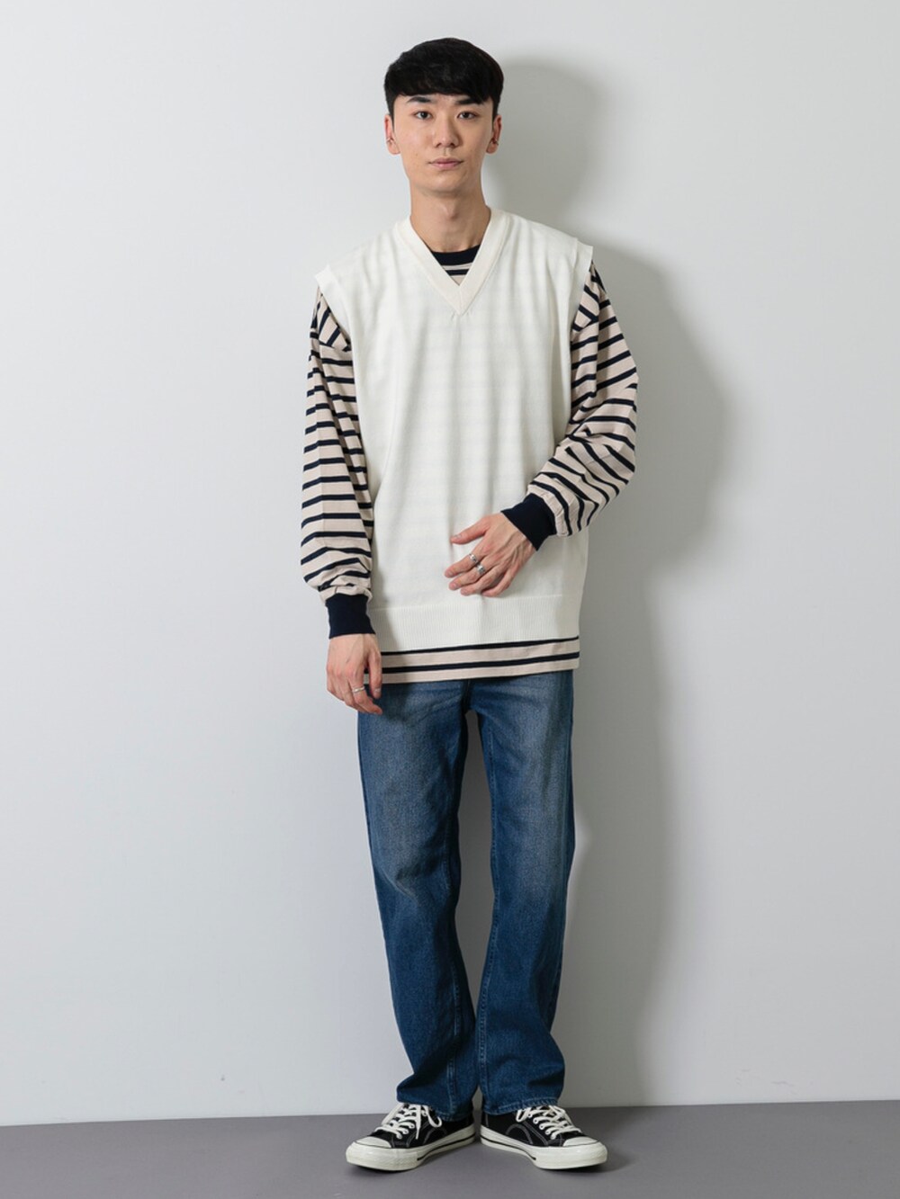 ブラック系のシューズ、ブルー系のデニムパンツ、ホワイト系のベストを着用したメンズの春コーディネートの2枚目の写真