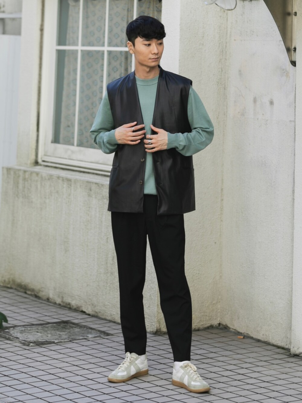 ホワイト系のスニーカー、ブラック系のスラックス、ブラック系のベストを着用したメンズの秋コーディネートの2枚目の写真