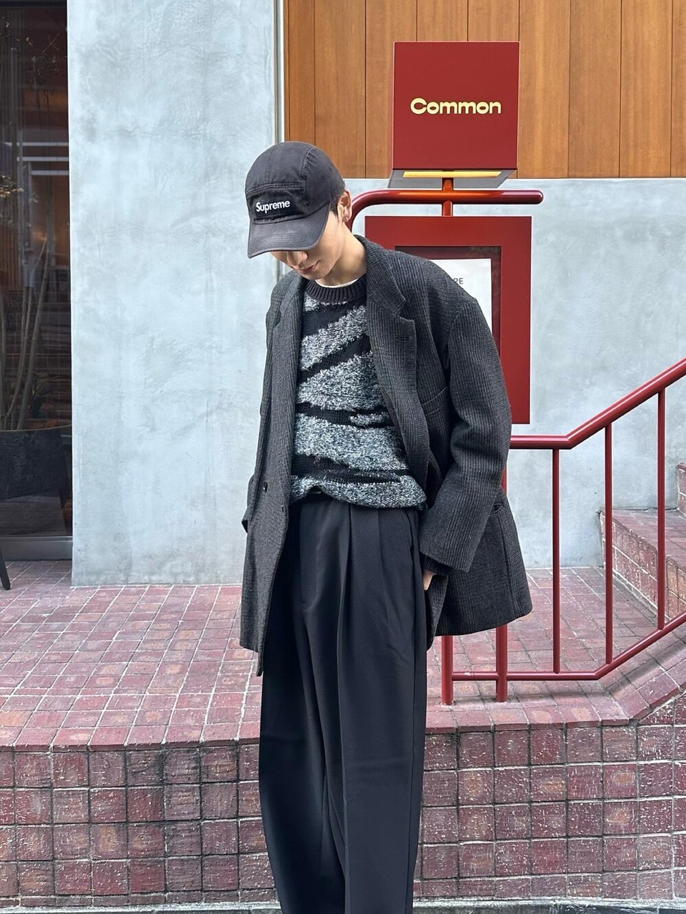 ブラック系のスニーカー、ブラック系のスラックス、ブラック系のニット/セーターを着用したメンズの冬コーディネートの4枚目の写真