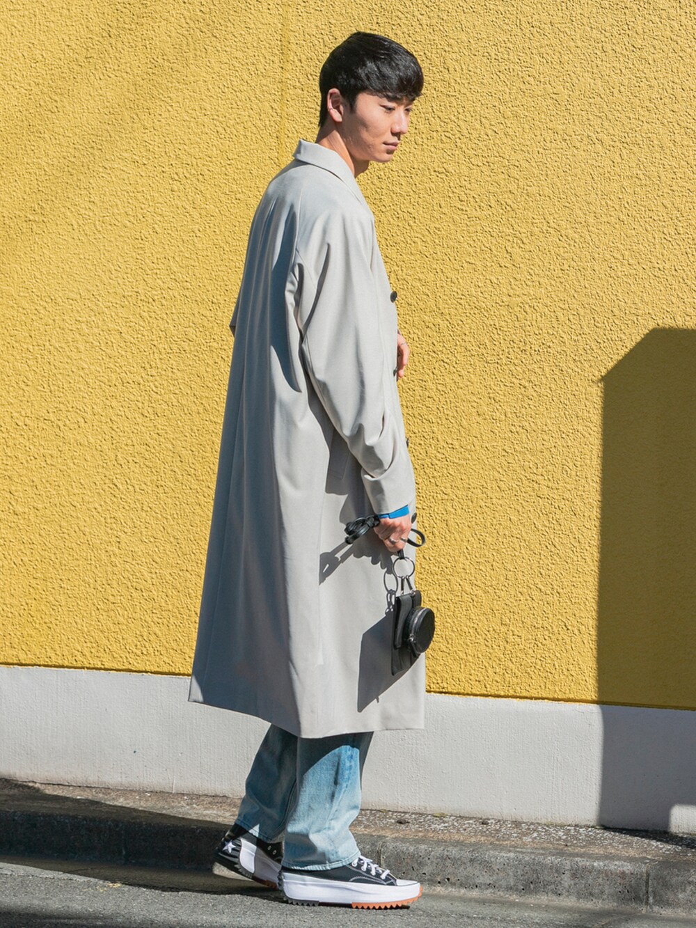 ブラック系のシューズ、ブルー系のデニムパンツ、ベージュ系のステンカラーコートを着用したメンズの冬コーディネートの2枚目の写真