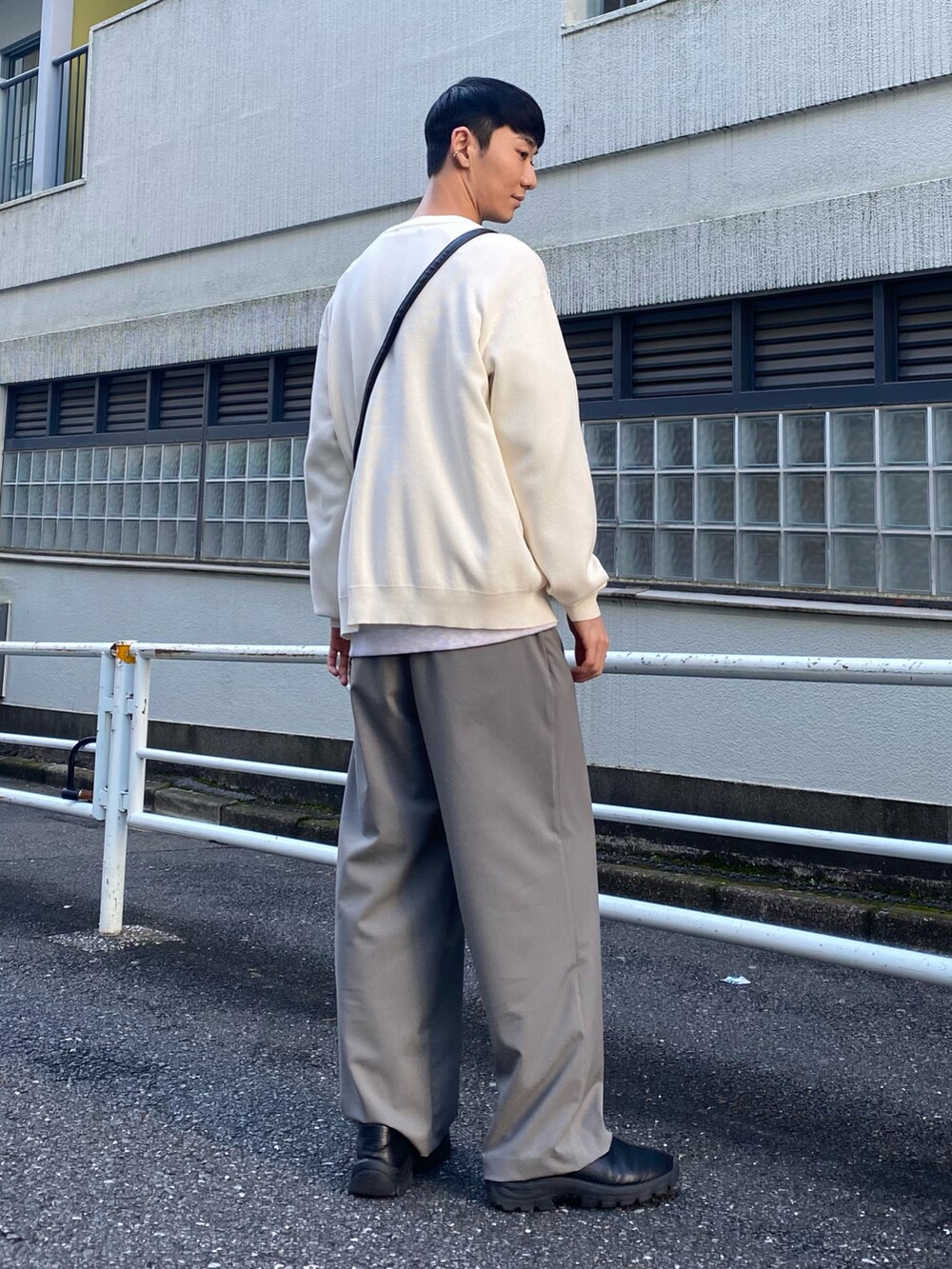 ブラック系のスリッポン、グレー系のスラックス、ホワイト系のカーディガン/ボレロを着用したメンズの冬コーディネートの2枚目の写真