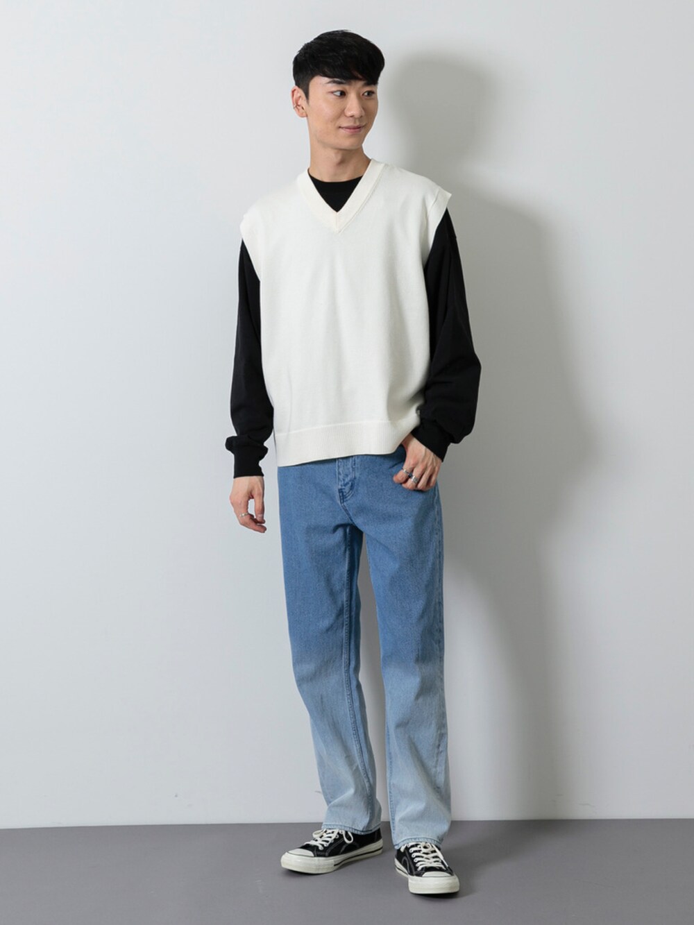 ブラック系のシューズ、ブルー系のデニムパンツ、ホワイト系のベストを着用したメンズの春コーディネートの2枚目の写真