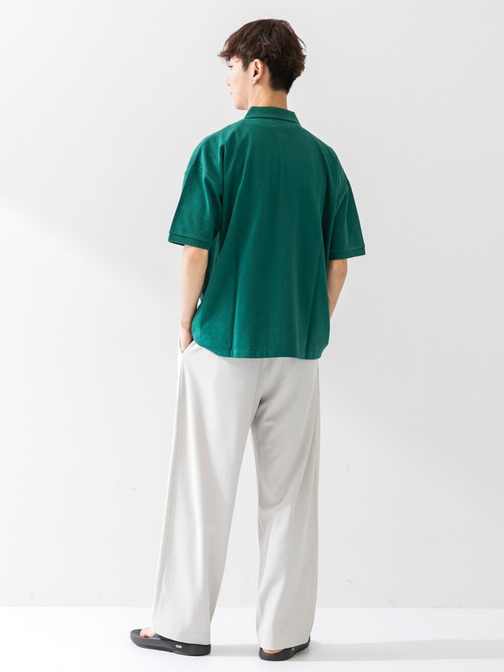 ブラック系のサンダル、ベージュ系のスラックス、グリーン系のポロシャツを着用したメンズの夏コーディネートの3枚目の写真