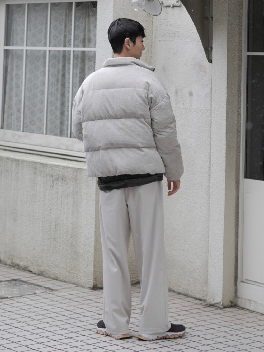 ベージュ系のスラックス、ベージュ系のダウンジャケット/コート、ブラック系のベストを着用したメンズの冬コーディネートの3枚目の写真