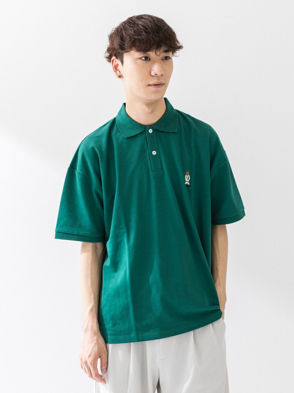 ブラック系のサンダル、ホワイト系のスラックス、グリーン系のポロシャツを着用したメンズの夏コーディネートの4枚目の写真