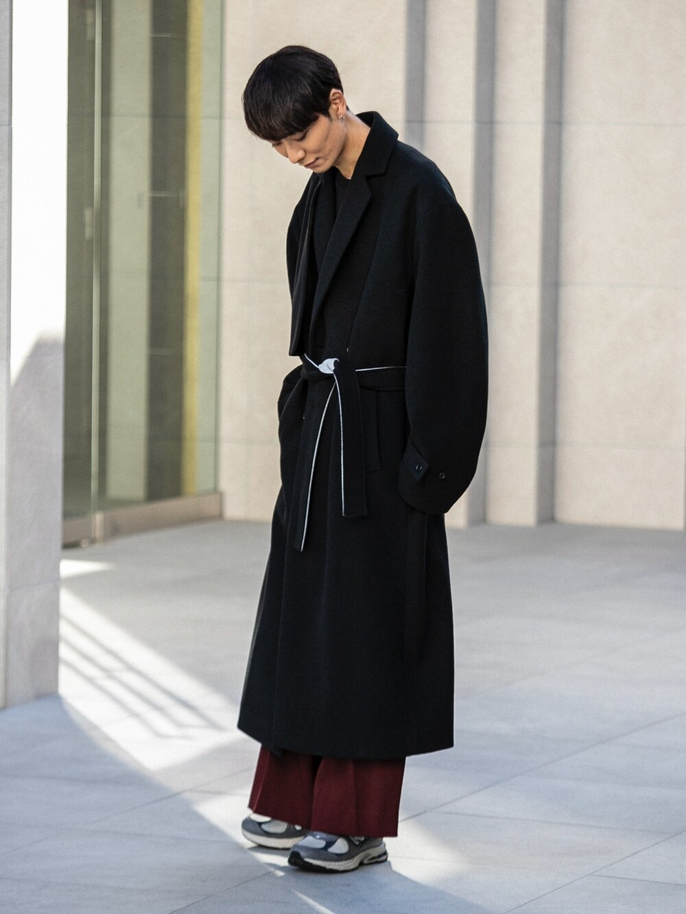 グレー系のその他シューズ、レッド系のその他パンツ、ブラック系のチェスターコートを着用したメンズの冬コーディネートの2枚目の写真