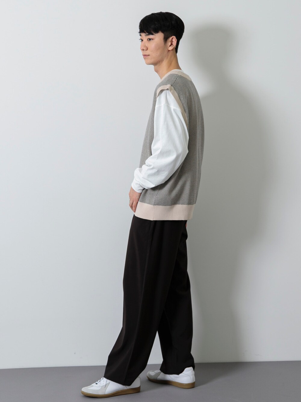 ホワイト系のスニーカー、ブラック系のその他パンツ、ベージュ系のベストを着用したメンズの冬コーディネートの3枚目の写真