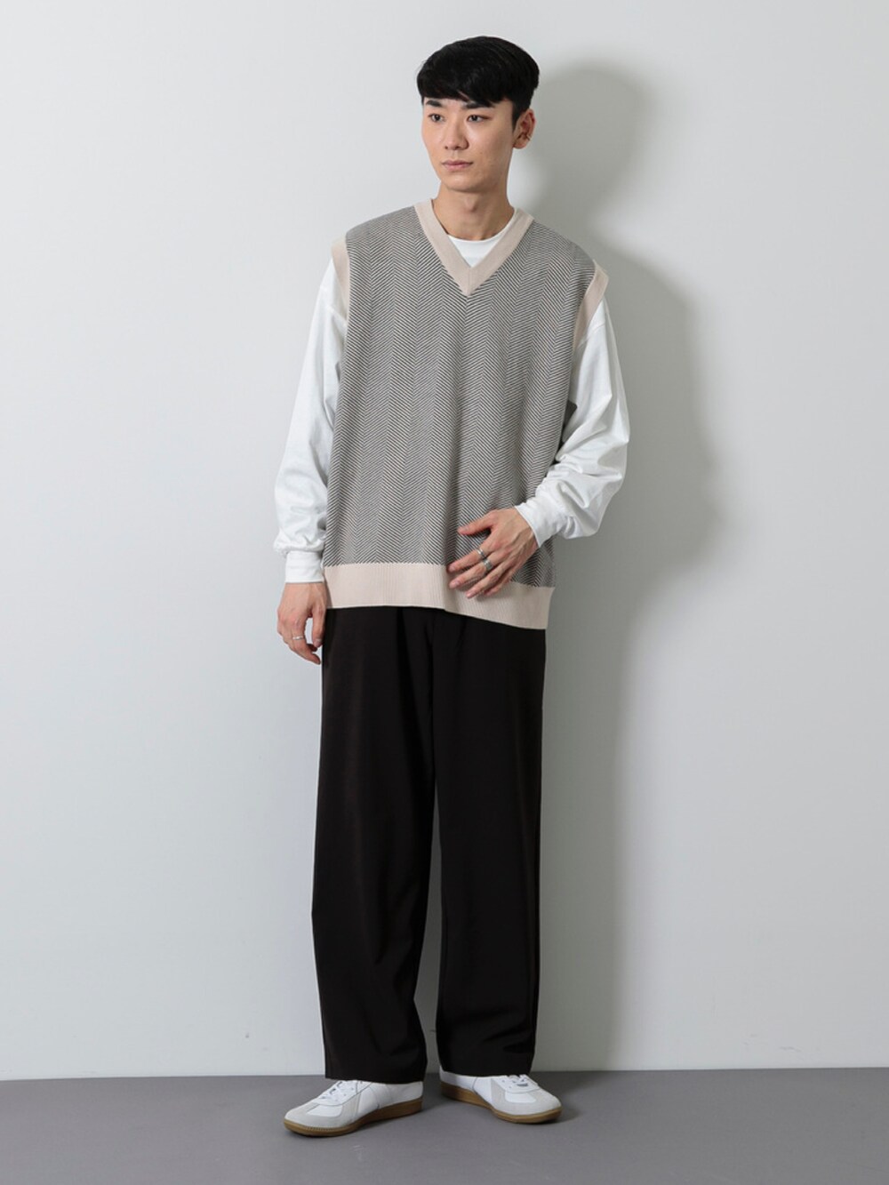 ホワイト系のスニーカー、ブラック系のその他パンツ、ベージュ系のベストを着用したメンズの冬コーディネートの2枚目の写真