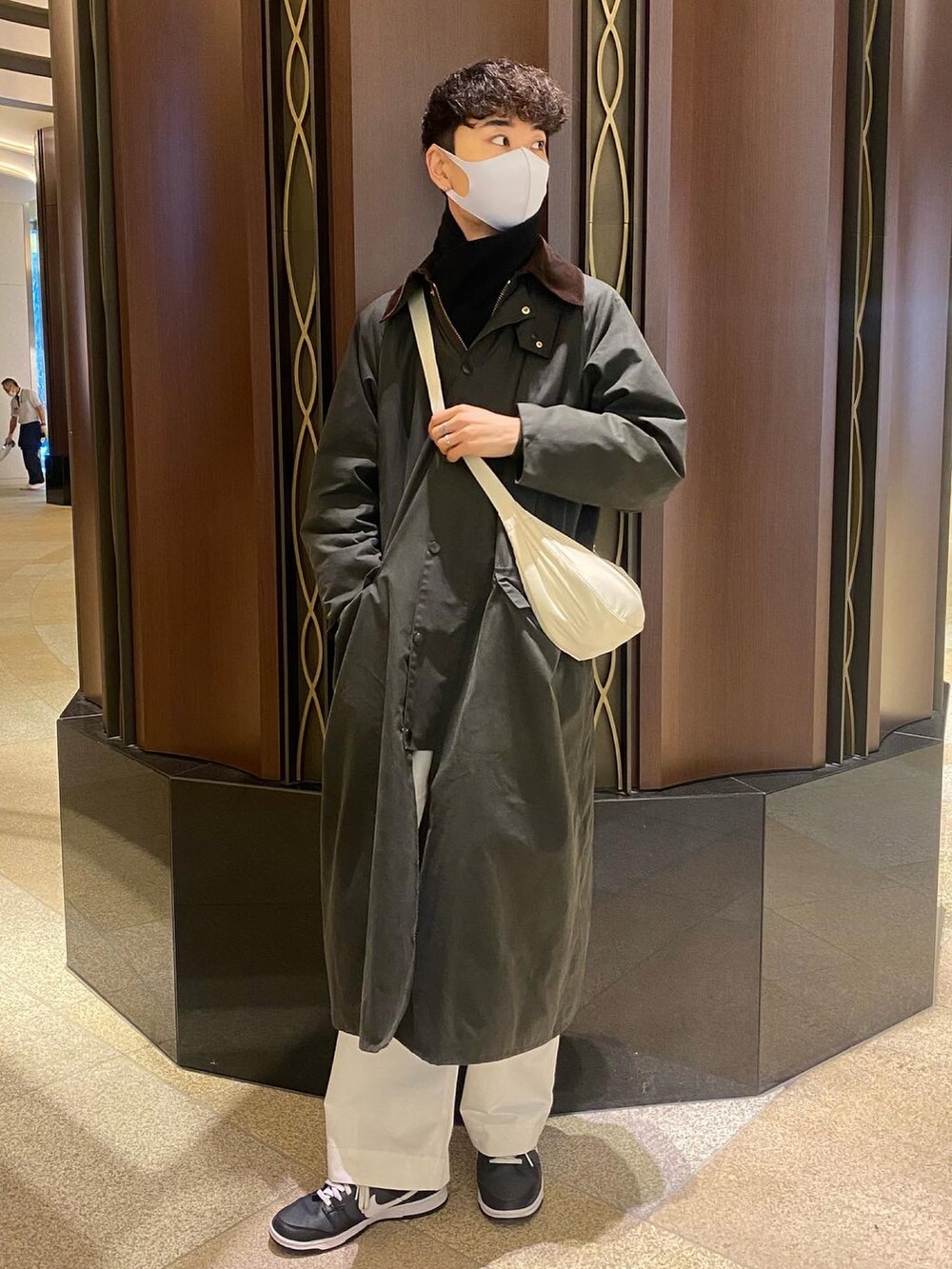 グリーン系のジャケット/アウター、ホワイト系のショルダーバッグ、ブラック系のニット/セーターを着用したメンズの冬コーディネートの2枚目の写真