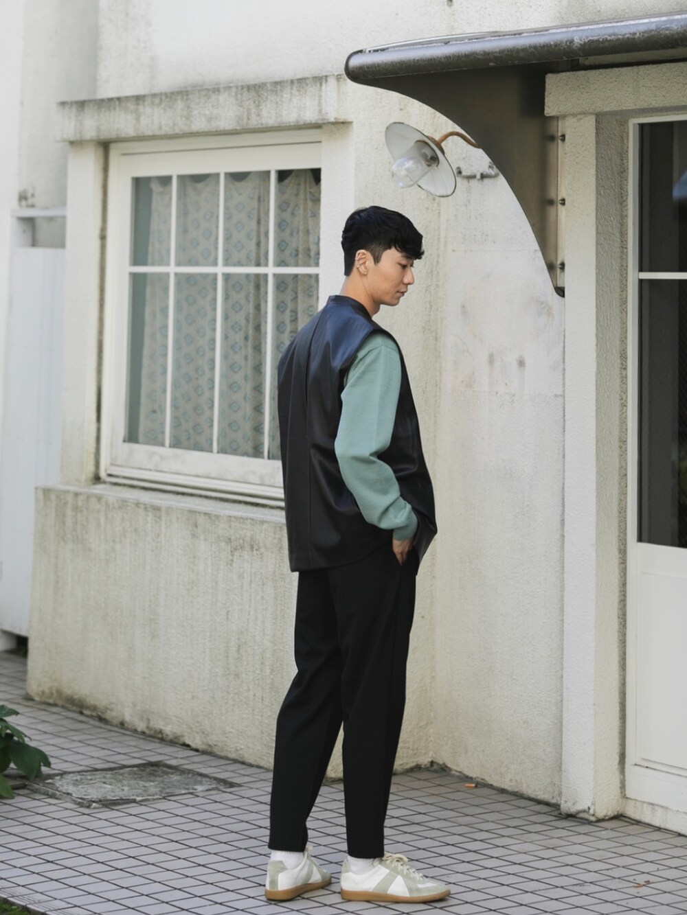 ホワイト系のスニーカー、ブラック系のスラックス、ブラック系のベストを着用したメンズの秋コーディネートの3枚目の写真