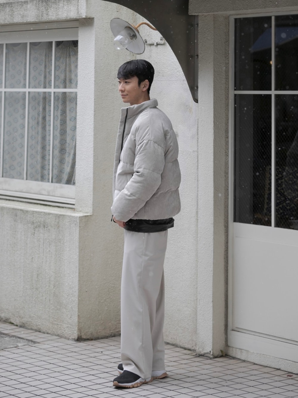 ベージュ系のスラックス、ベージュ系のダウンジャケット/コート、ブラック系のベストを着用したメンズの冬コーディネートの2枚目の写真