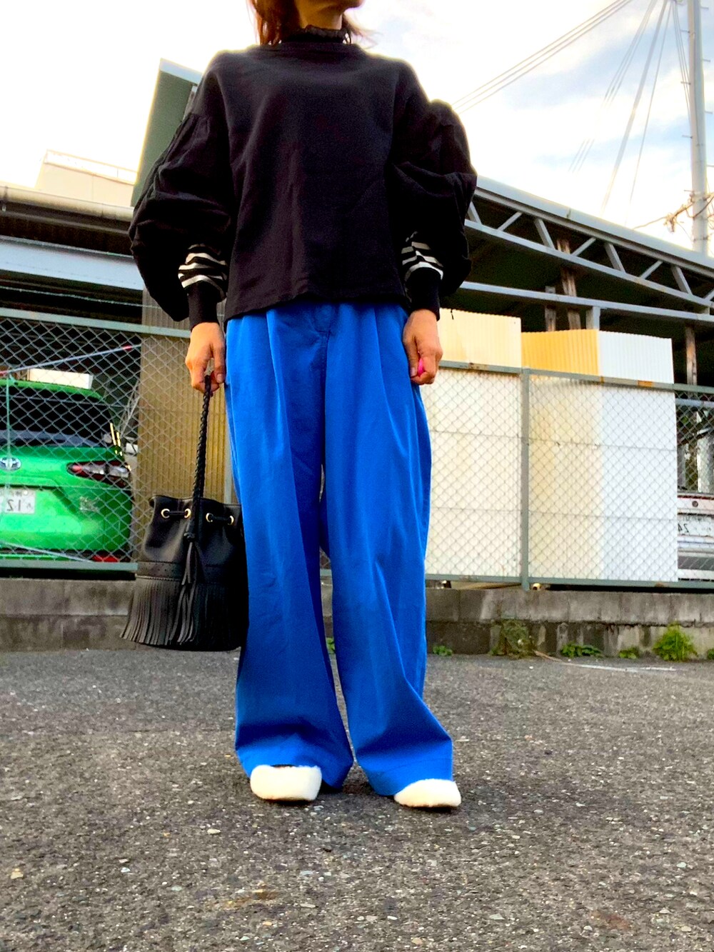 ブラック系のニット/セーター、ブルー系のパンツ、ホワイト系のシューズを着用したレディースの秋コーディネートの2枚目の写真