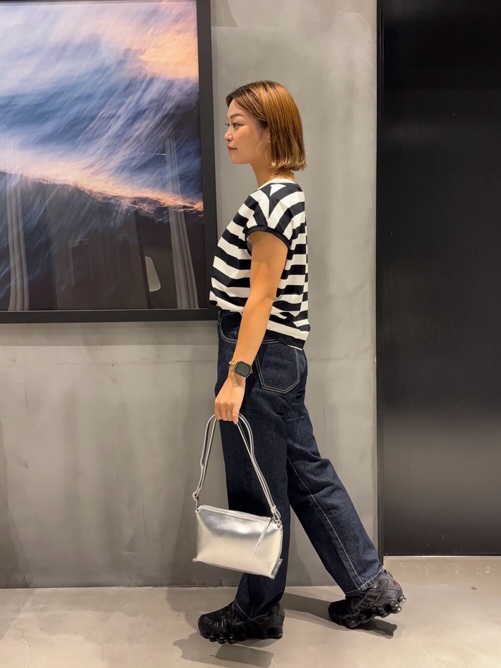 シルバー系のショルダーバッグ、ブラック系のTシャツ/カットソー、ブルー系のデニムパンツを着用したレディースの夏コーディネートの3枚目の写真