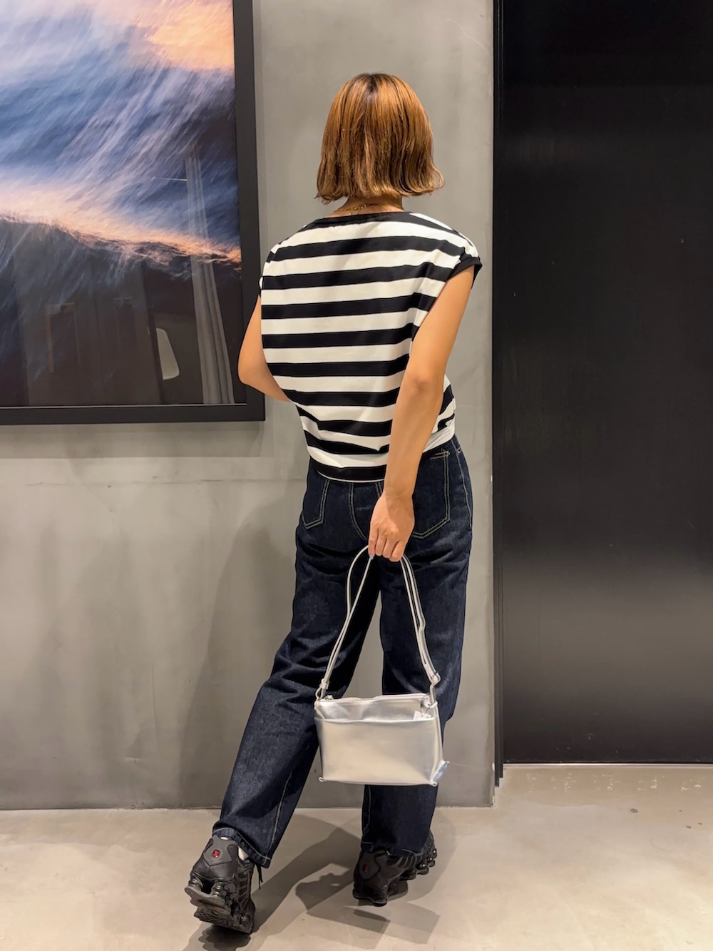 シルバー系のショルダーバッグ、ブラック系のTシャツ/カットソー、ブルー系のデニムパンツを着用したレディースの夏コーディネートの2枚目の写真