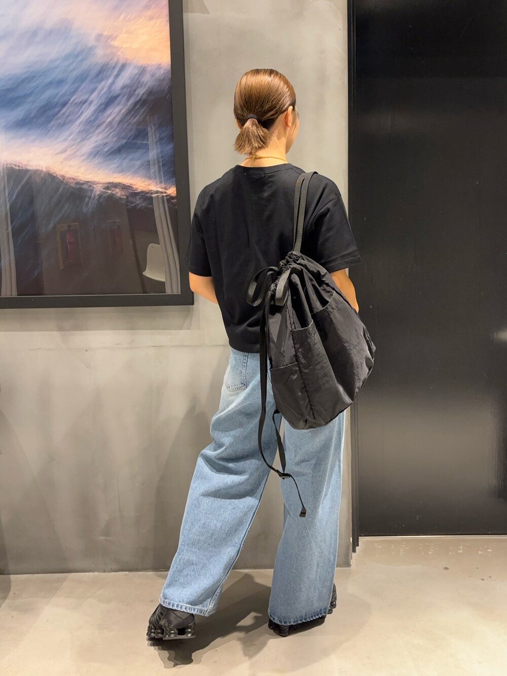 ブラック系のTシャツ/カットソー、ブルー系のデニムパンツ、ブラック系のバックパック/リュックを着用したレディースの夏コーディネートの2枚目の写真