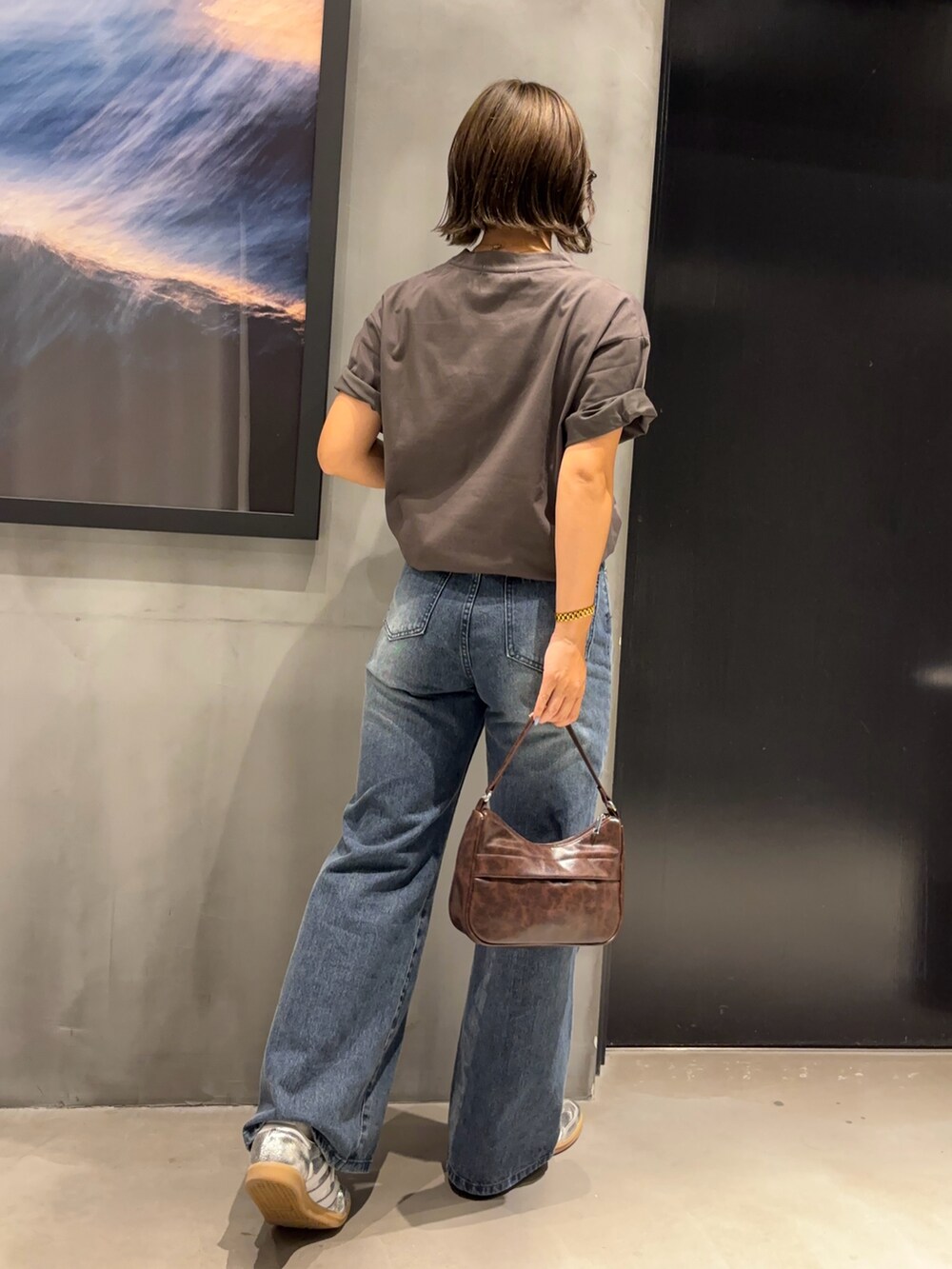 ホワイト系のTシャツ/カットソー、ブルー系のデニムパンツ、ブラウン系のハンドバッグを着用したレディースの夏コーディネートの2枚目の写真