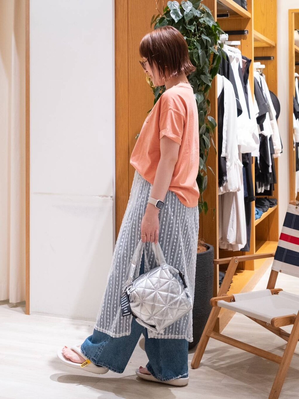 ベージュ系のサンダル、オレンジ系のTシャツ/カットソー、ブルー系のデニムパンツを着用したレディースの夏コーディネートの2枚目の写真