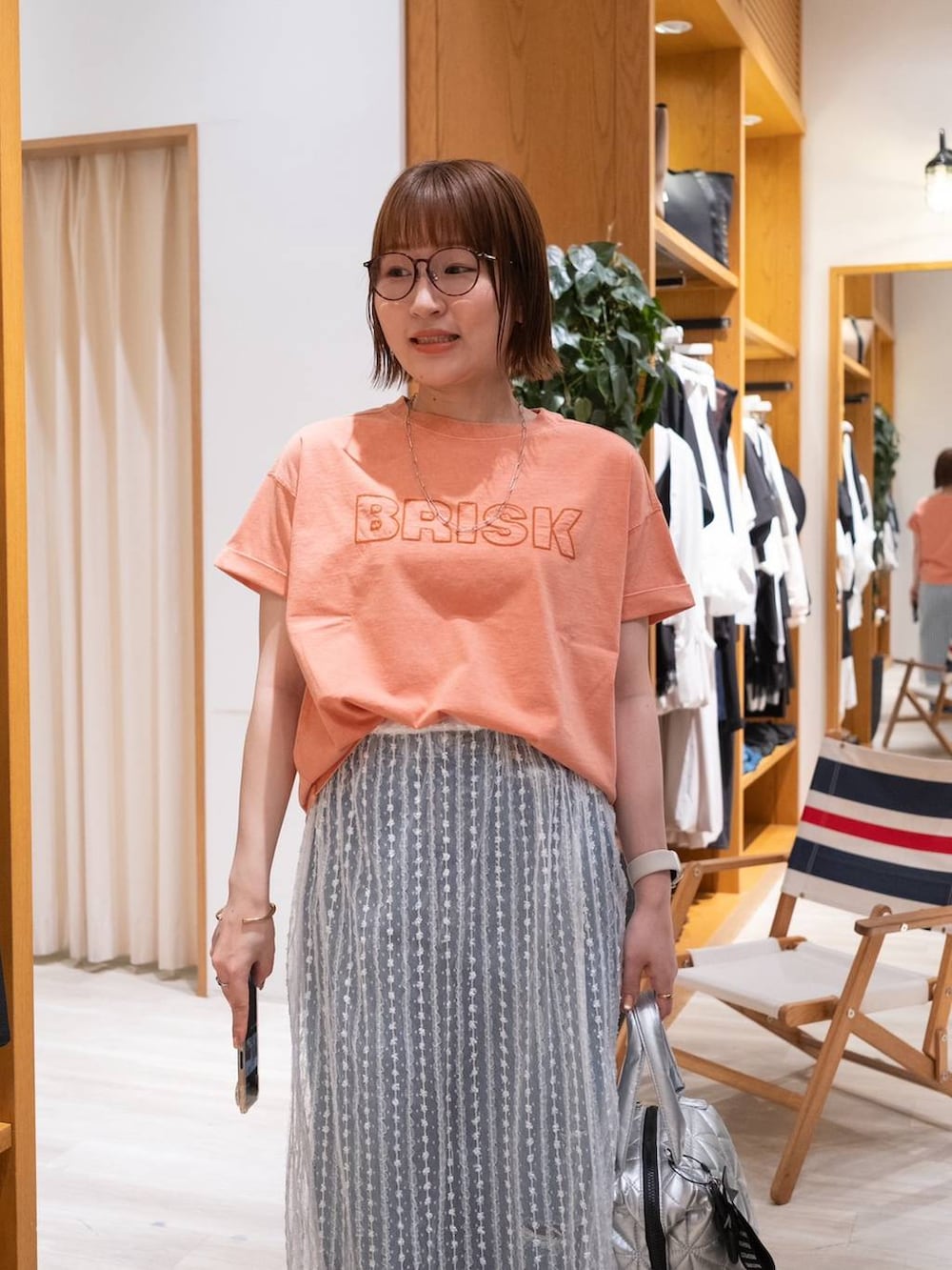 ベージュ系のサンダル、オレンジ系のTシャツ/カットソー、ブルー系のデニムパンツを着用したレディースの夏コーディネートの6枚目の写真