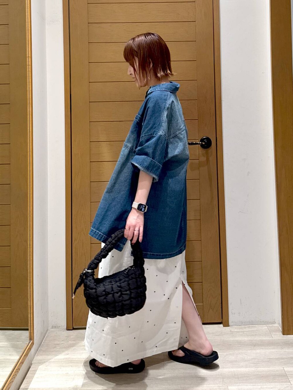 ブラック系のハンドバッグ、ブルー系のシャツ/ブラウス、イエロー系のベストを着用したレディースの夏コーディネートの3枚目の写真