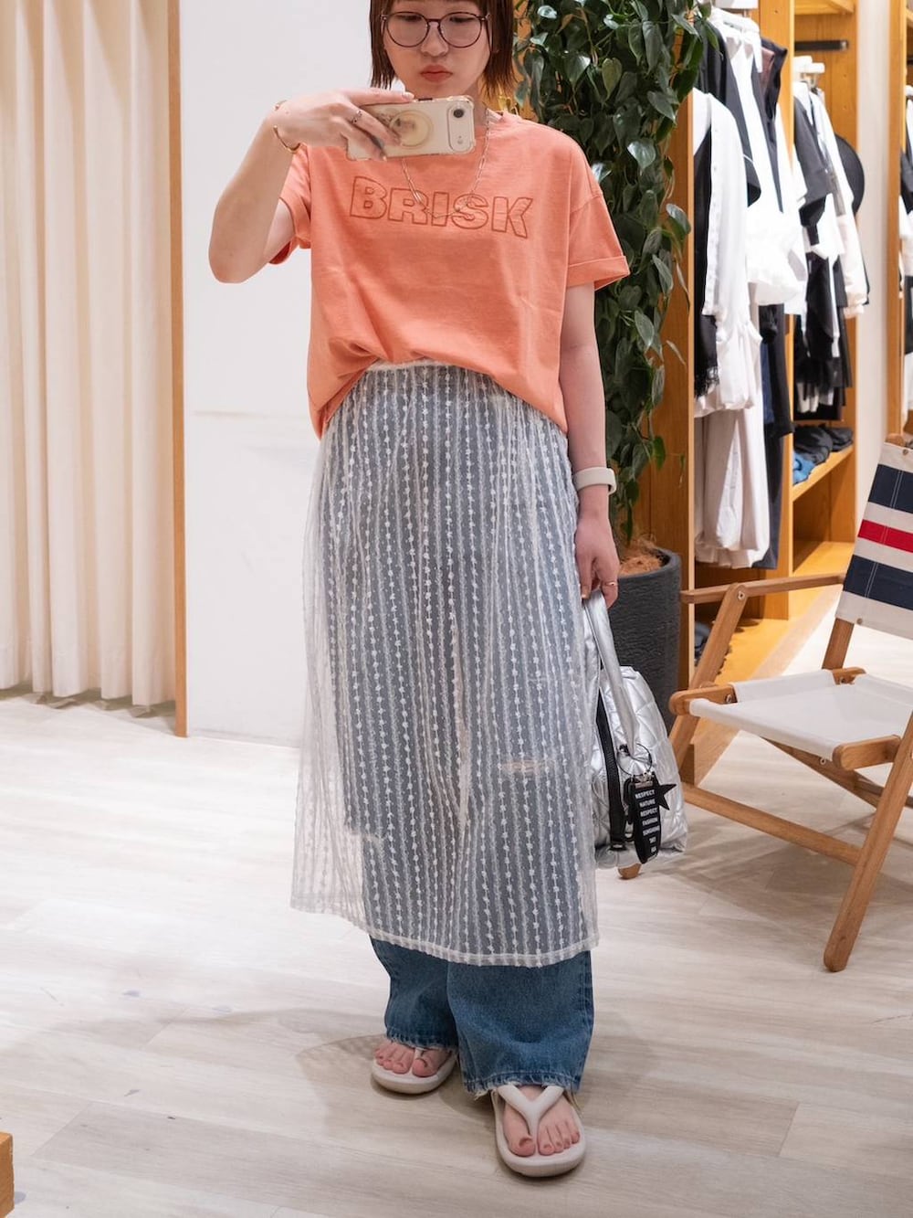 ベージュ系のサンダル、オレンジ系のTシャツ/カットソー、ブルー系のデニムパンツを着用したレディースの夏コーディネートの5枚目の写真