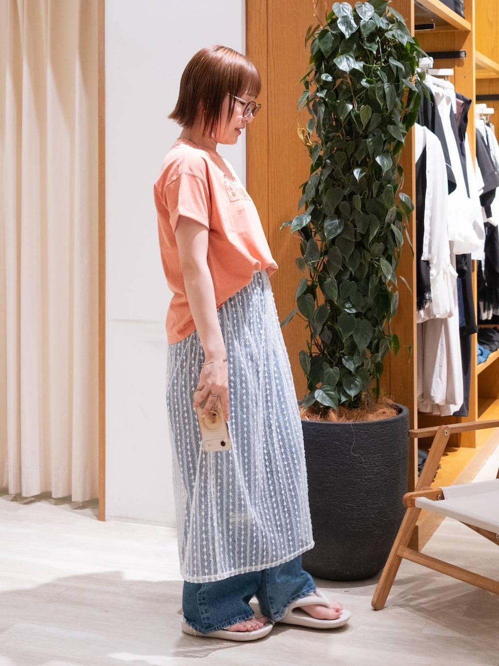 ベージュ系のサンダル、オレンジ系のTシャツ/カットソー、ブルー系のデニムパンツを着用したレディースの夏コーディネートの4枚目の写真