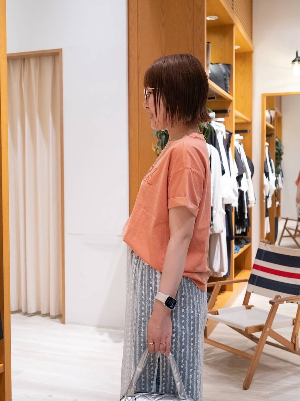 ベージュ系のサンダル、オレンジ系のTシャツ/カットソー、ブルー系のデニムパンツを着用したレディースの夏コーディネートの7枚目の写真