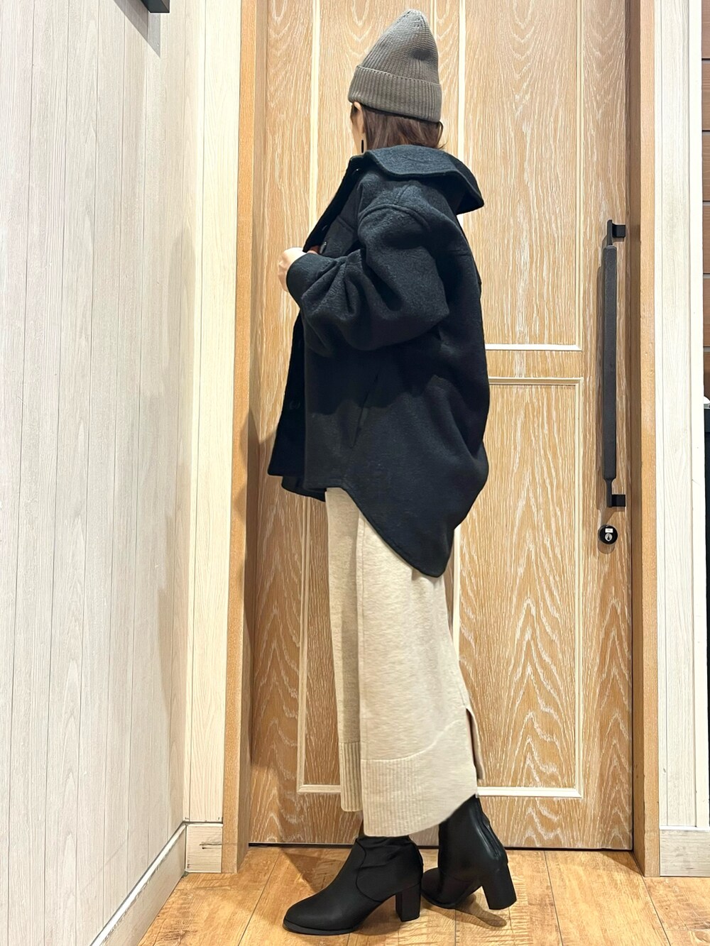 ブラック系のテーラードジャケット、ベージュ系のワンピース、ブラック系のブーツを着用したレディースの秋コーディネートの2枚目の写真