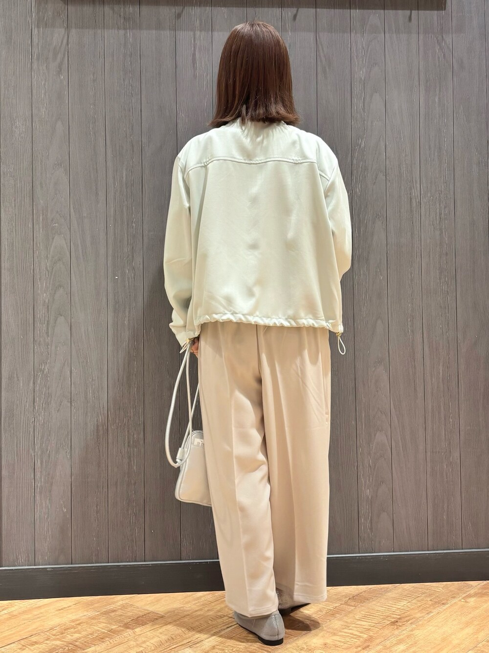 グリーン系のブルゾン、ホワイト系のニット/セーター、ベージュ系のその他パンツを着用したレディースの春コーディネートの3枚目の写真