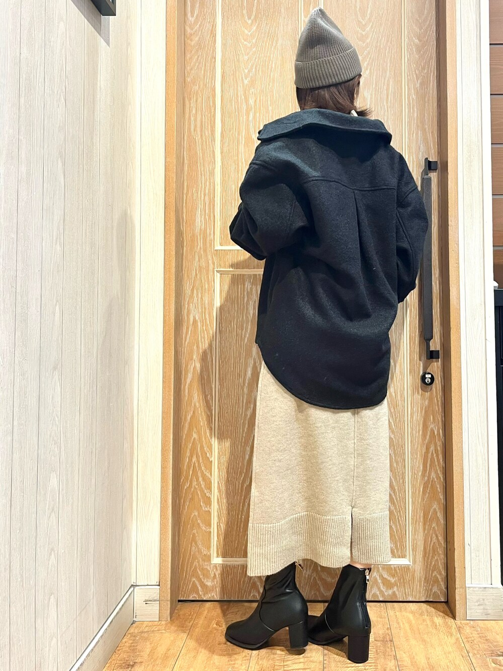 ブラック系のテーラードジャケット、ベージュ系のワンピース、ブラック系のブーツを着用したレディースの秋コーディネートの3枚目の写真