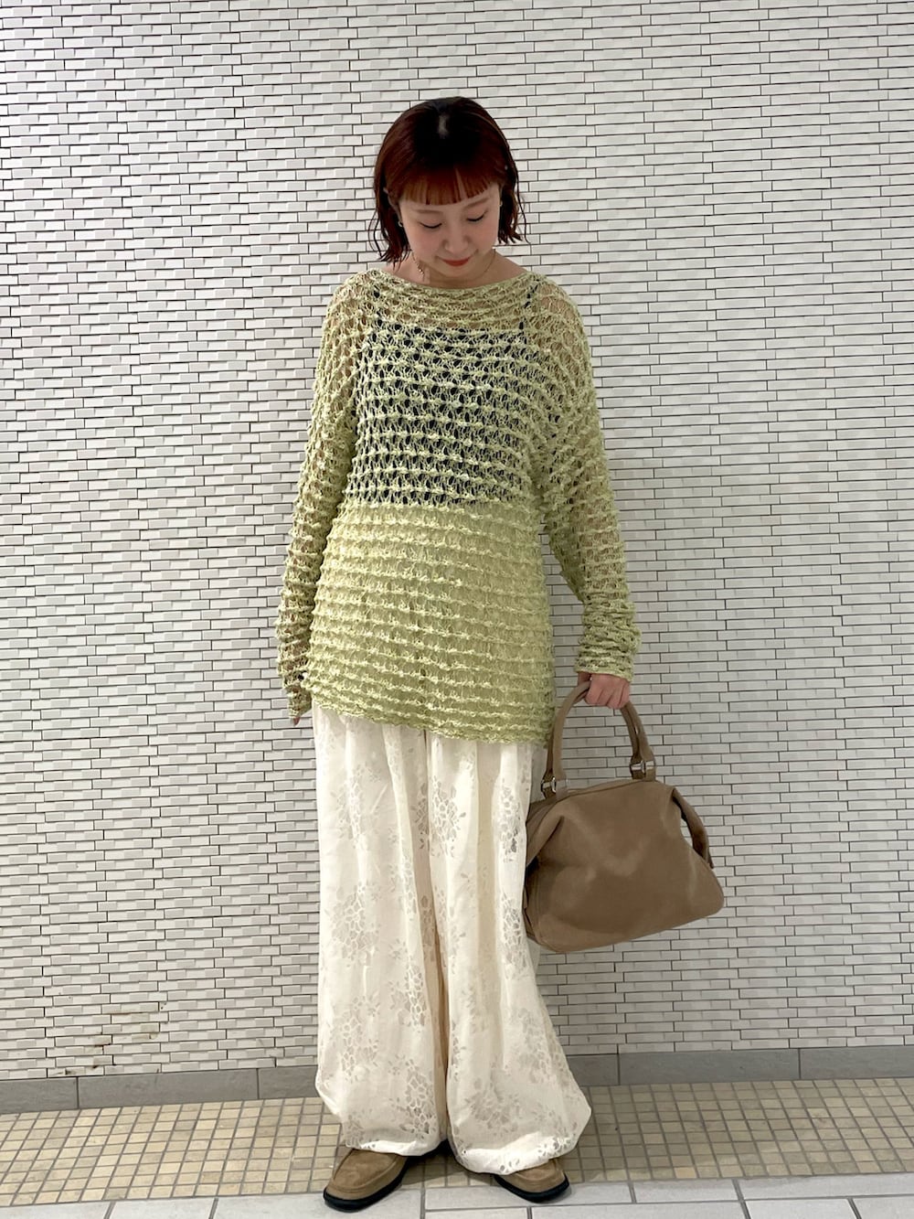 グリーン系のニット/セーター、ホワイト系のその他パンツ、ベージュ系のボストンバッグを着用したレディースの春コーディネートの3枚目の写真