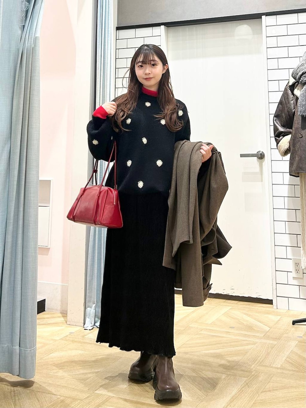 ブラウン系のブーツ、ブラウン系のステンカラーコート、レッド系のニット/セーターを着用したレディースの冬コーディネートの3枚目の写真