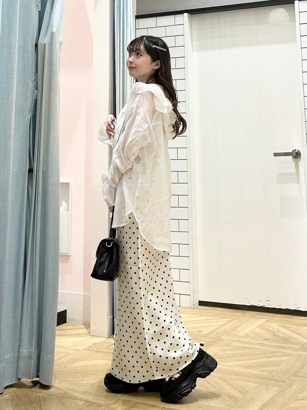 ホワイト系のスカート、シルバー系のタンクトップ、ブラック系のスニーカーを着用したレディースの夏コーディネートの4枚目の写真