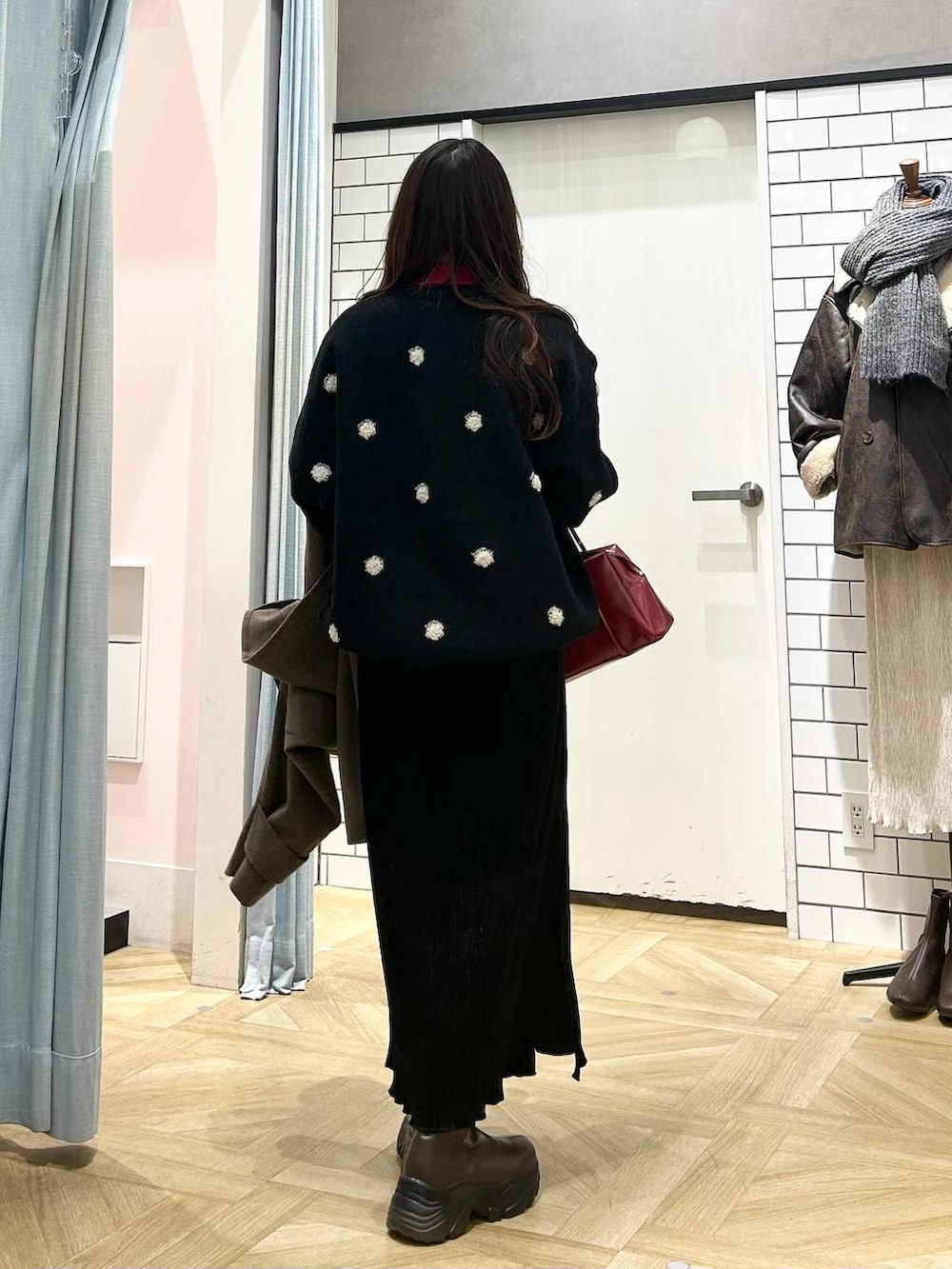 ブラウン系のブーツ、ブラウン系のステンカラーコート、レッド系のニット/セーターを着用したレディースの冬コーディネートの2枚目の写真