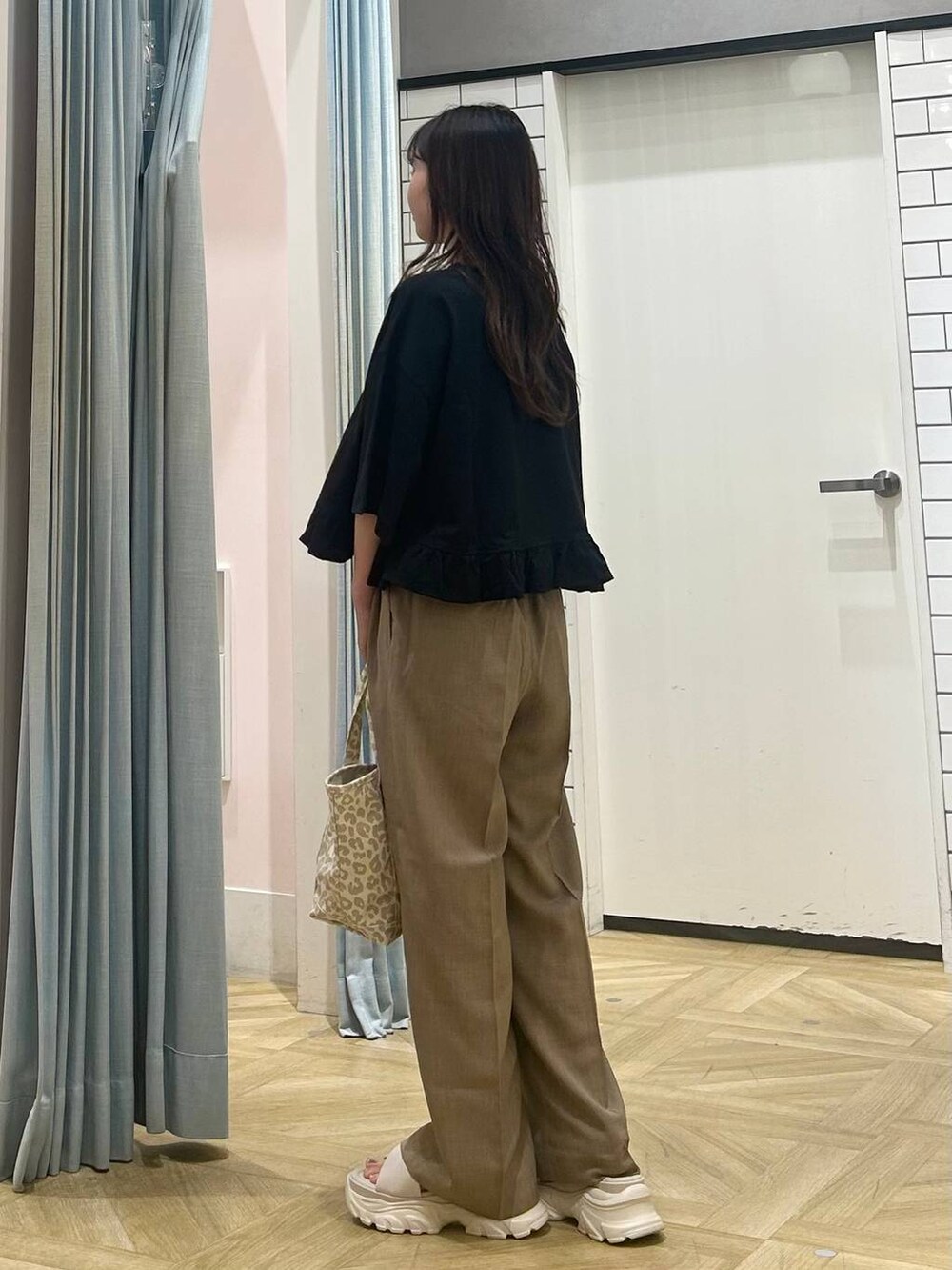 ホワイト系のサンダル、ベージュ系のショルダーバッグ、ベージュ系のスラックスを着用したレディースの夏コーディネートの2枚目の写真