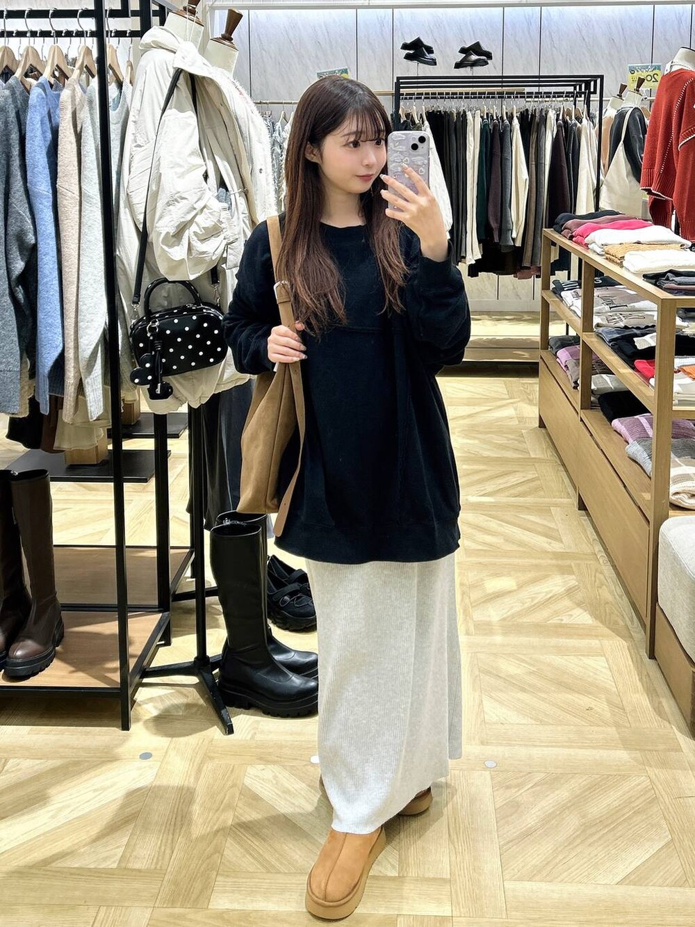 グレー系のスカート、ベージュ系のショルダーバッグ、ブラック系のスウェットを着用したレディースの秋コーディネートの2枚目の写真