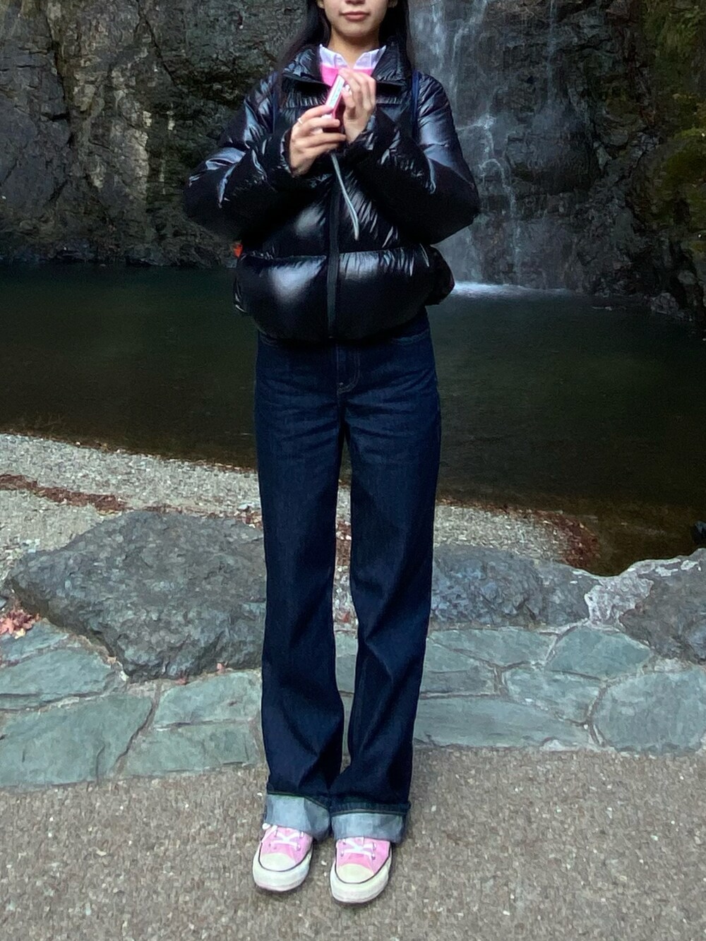 ピンク系のスニーカー、ブルー系のデニムパンツ、ブラック系のダウンジャケット/コートを着用したレディースの冬コーディネートの2枚目の写真