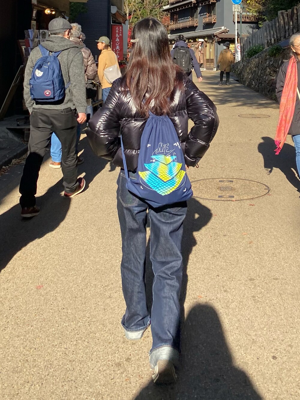 ピンク系のスニーカー、ブルー系のデニムパンツ、ブラック系のダウンジャケット/コートを着用したレディースの冬コーディネートの4枚目の写真