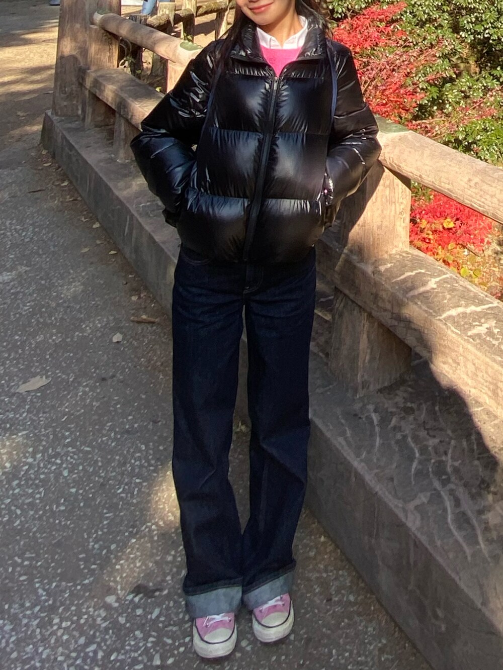 ピンク系のスニーカー、ブルー系のデニムパンツ、ブラック系のダウンジャケット/コートを着用したレディースの冬コーディネートの3枚目の写真