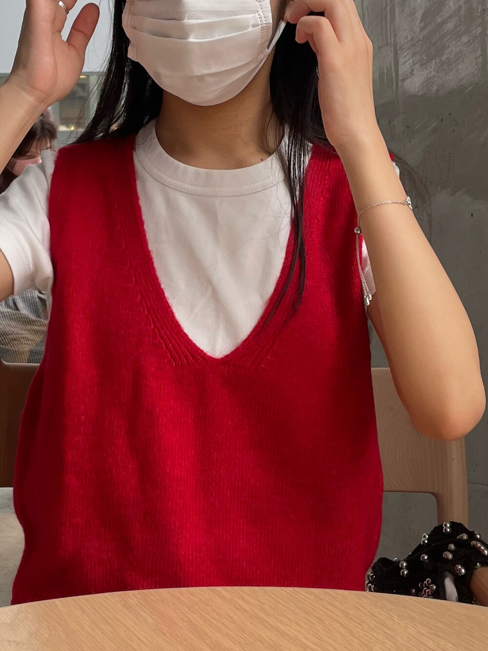 レッド系のベスト、ブルー系のデニムパンツ、ホワイト系のスニーカーを着用したレディースの秋コーディネートの3枚目の写真