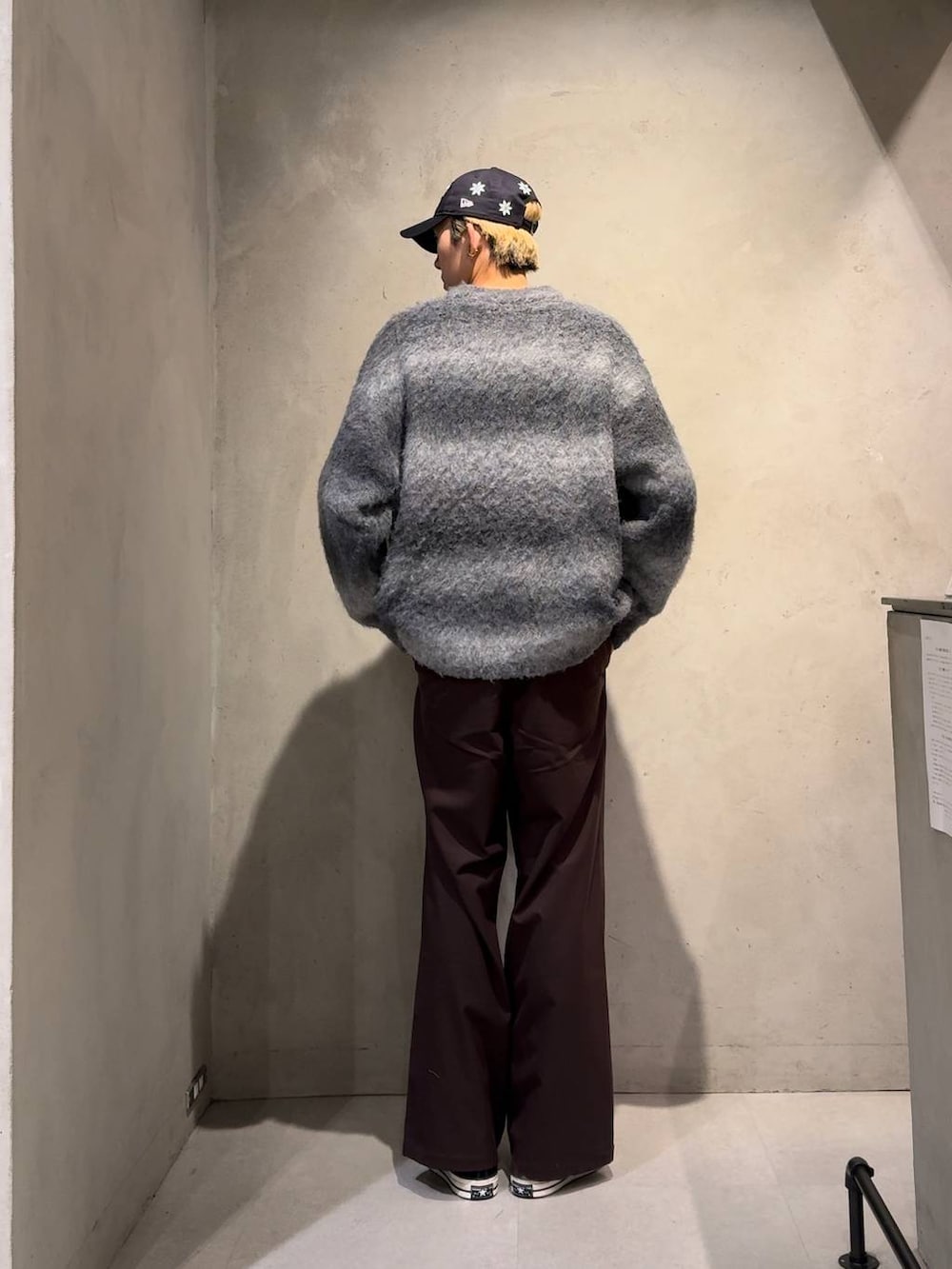 ブラウン系のスラックス、ブラック系のニット/セーター、ブルー系のキャップを着用したメンズの冬コーディネートの4枚目の写真