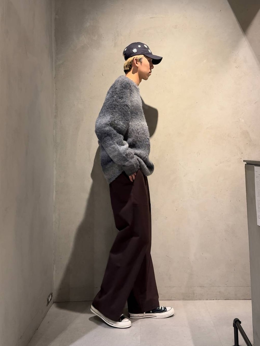 ブラウン系のスラックス、ブラック系のニット/セーター、ブルー系のキャップを着用したメンズの冬コーディネートの3枚目の写真