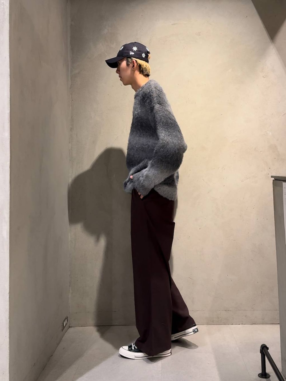 ブラウン系のスラックス、ブラック系のニット/セーター、ブルー系のキャップを着用したメンズの冬コーディネートの2枚目の写真