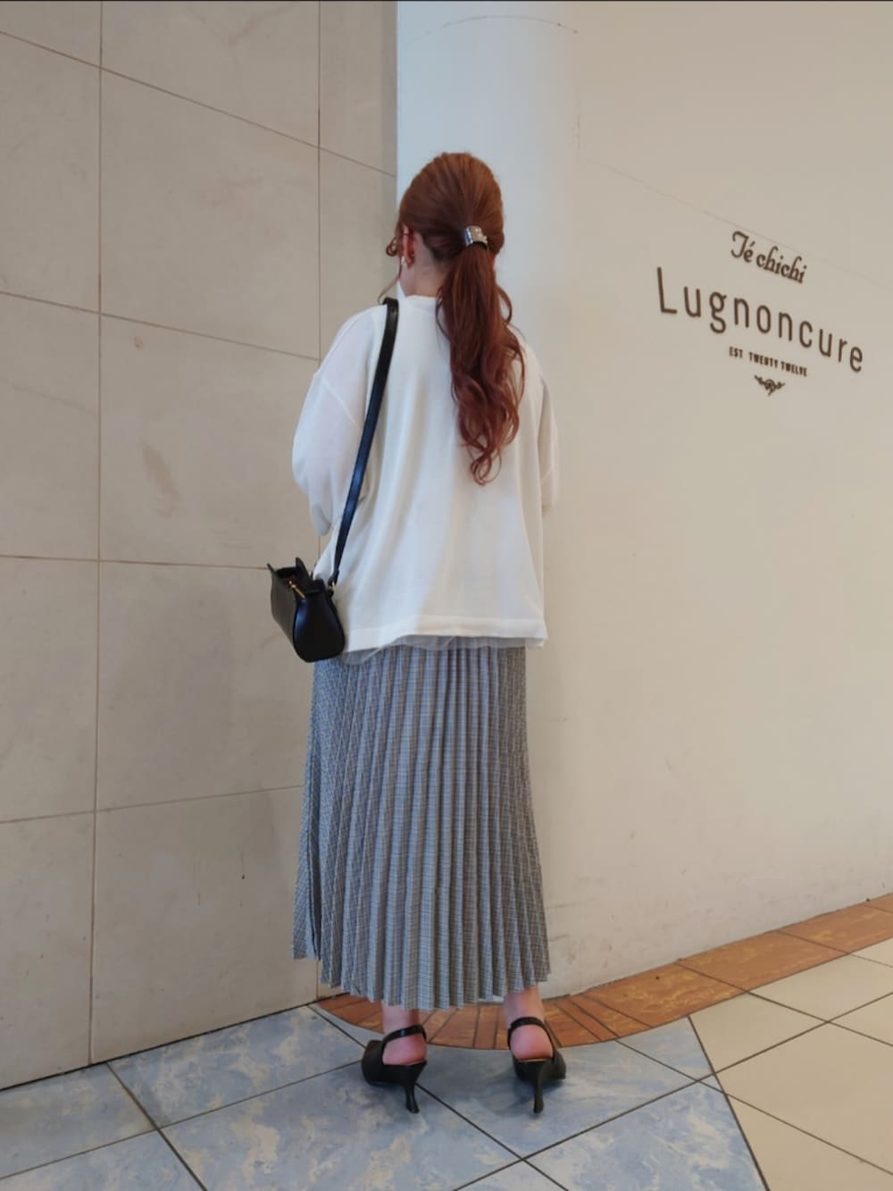 ブラック系のパンプス、ホワイト系のニット/セーター、ブラック系のハンドバッグを着用したレディースの春コーディネートの4枚目の写真