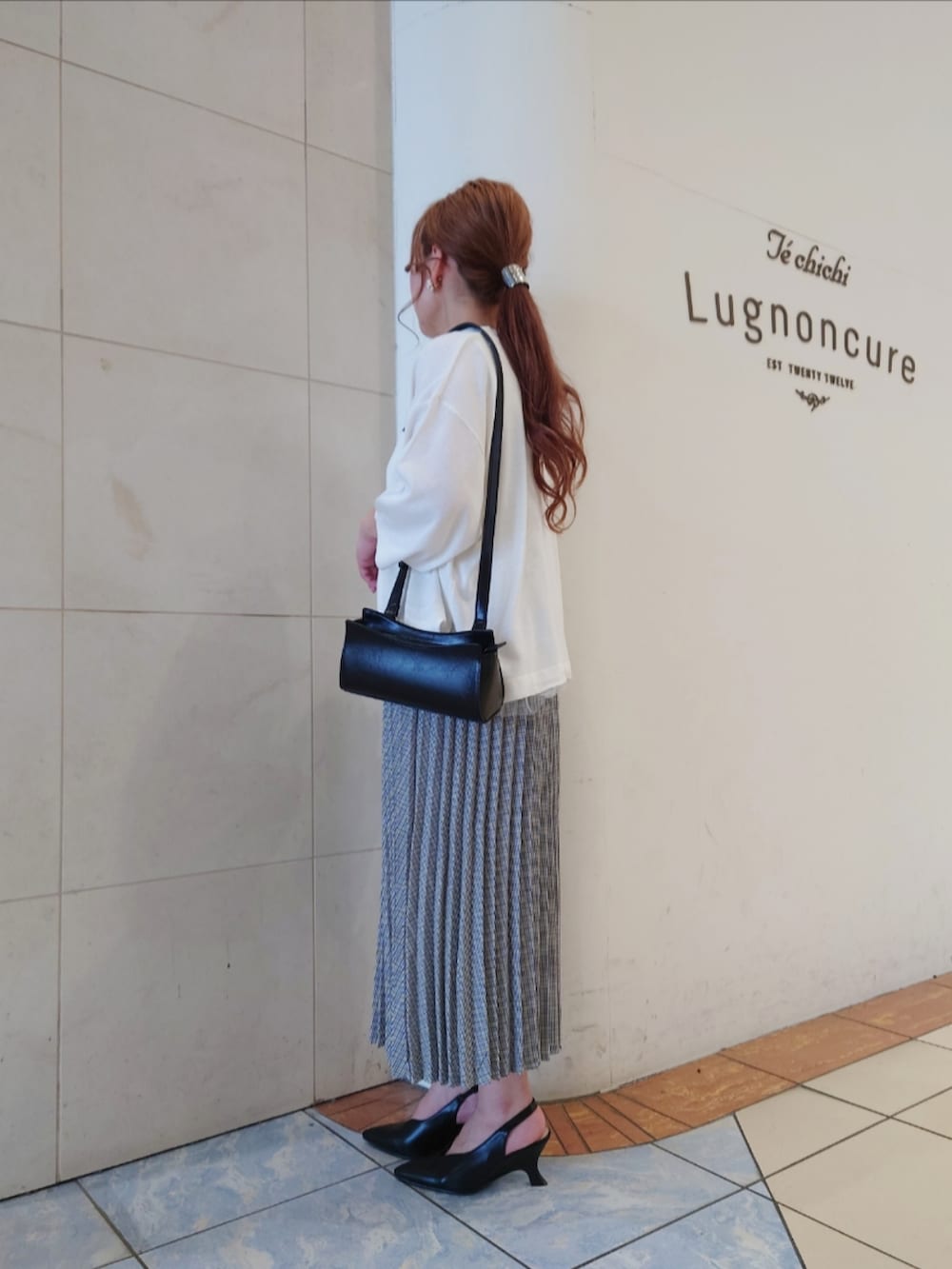 ブラック系のパンプス、ホワイト系のニット/セーター、ブラック系のハンドバッグを着用したレディースの春コーディネートの3枚目の写真