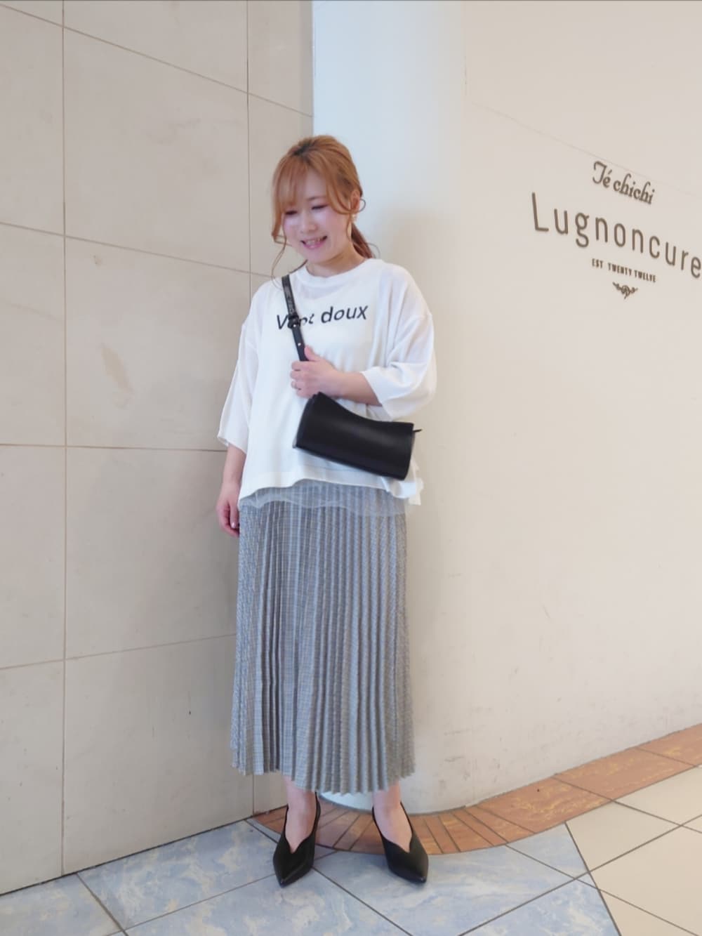 ブラック系のパンプス、ホワイト系のニット/セーター、ブラック系のハンドバッグを着用したレディースの春コーディネートの2枚目の写真