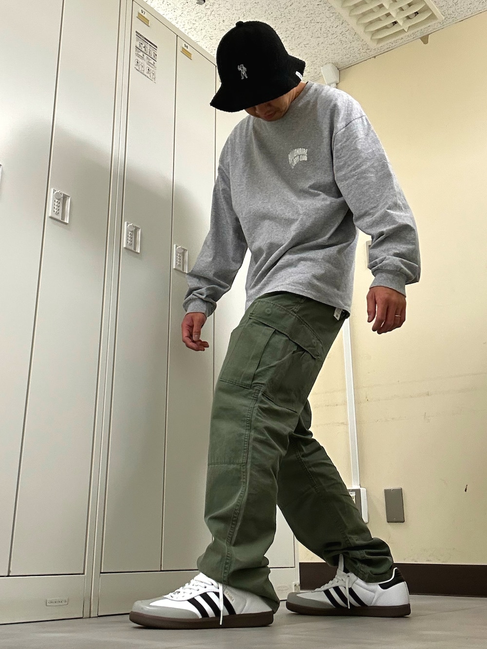 グレー系のTシャツ/カットソー、グリーン系のカーゴパンツ、ホワイト系のスニーカーを着用したメンズの春コーディネートの2枚目の写真