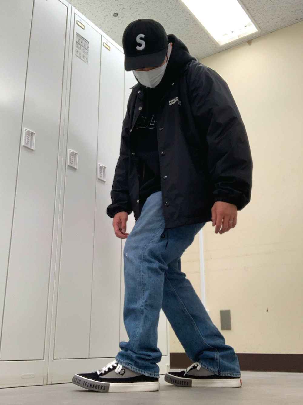 ブラック系のパーカー、ブラック系のナイロンジャケット、ブルー系のデニムパンツを着用したメンズの春コーディネートの2枚目の写真